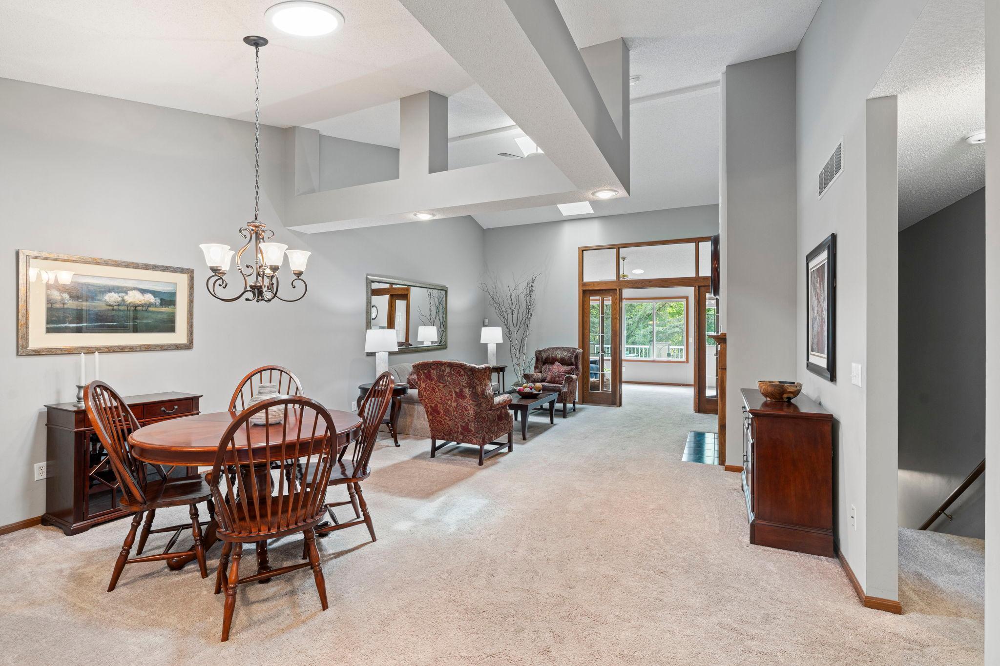 Dramatic great room has soaring vaulted ceilings, a skylight and suntube. View of french doors with transom windows leading into the sunroom.