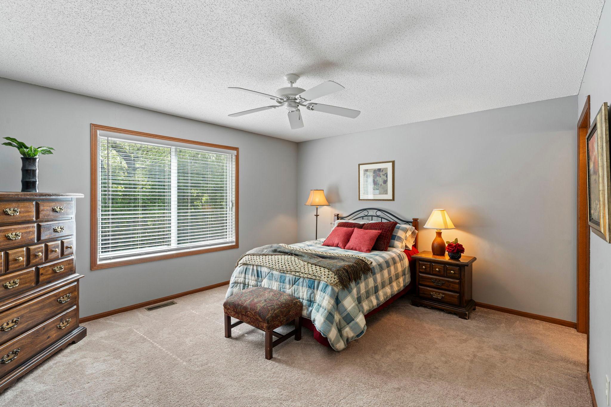 Spacious primary suite has views of your treed backyard.