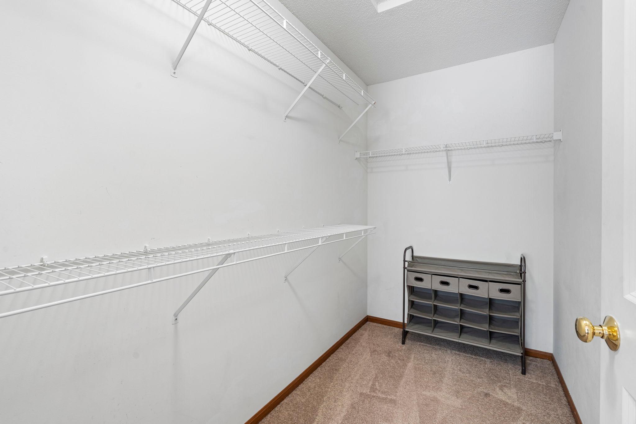 Large walk-in closet with built-in shelving in primary bedroom.