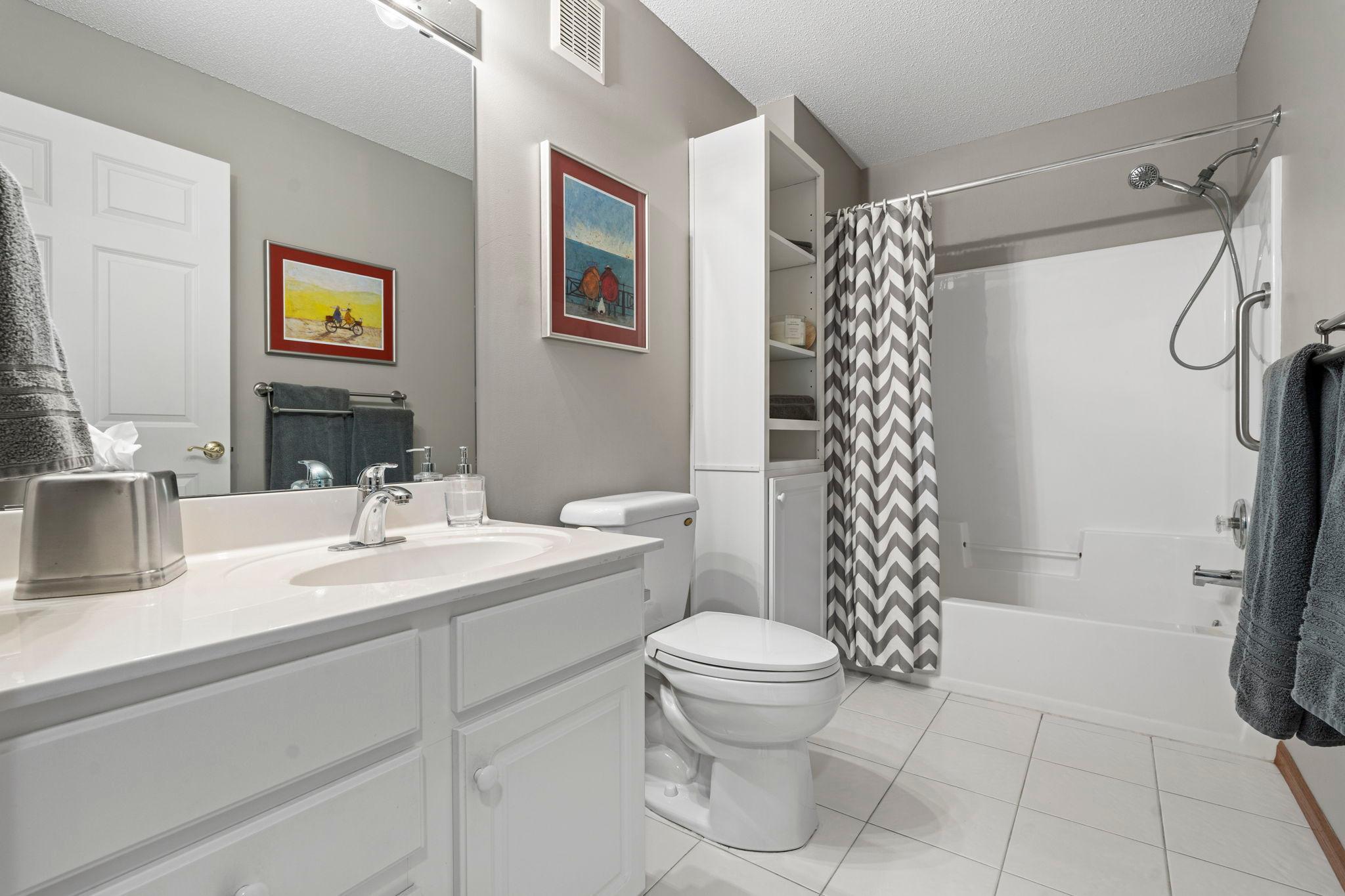 Main floor full bath will built-in white cabinets next to the tub.