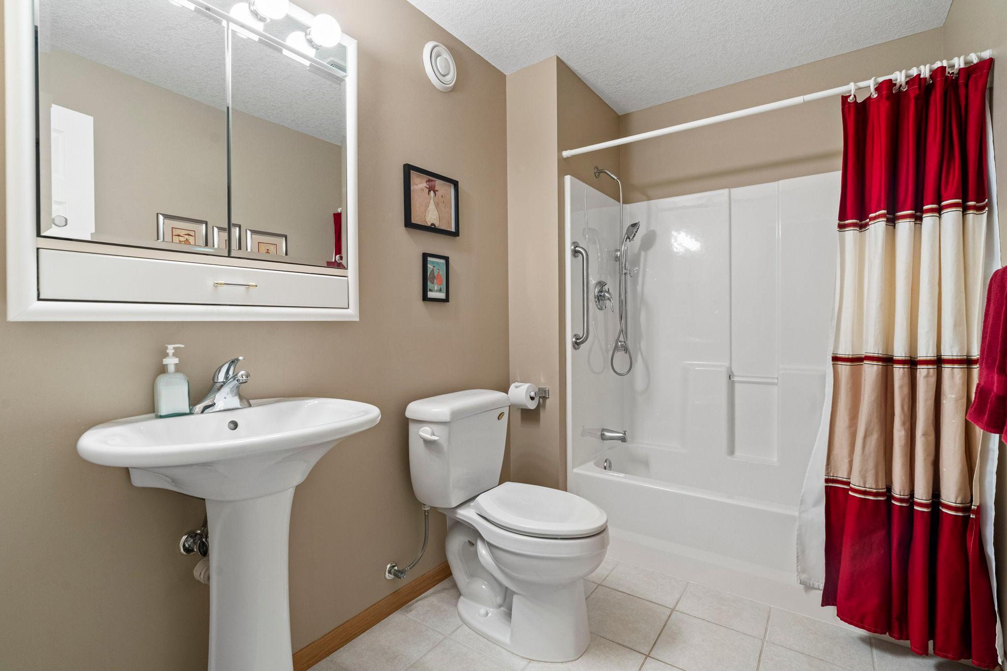 Full bath in the lower level has sparkling tub surround and ceramic tile floor.