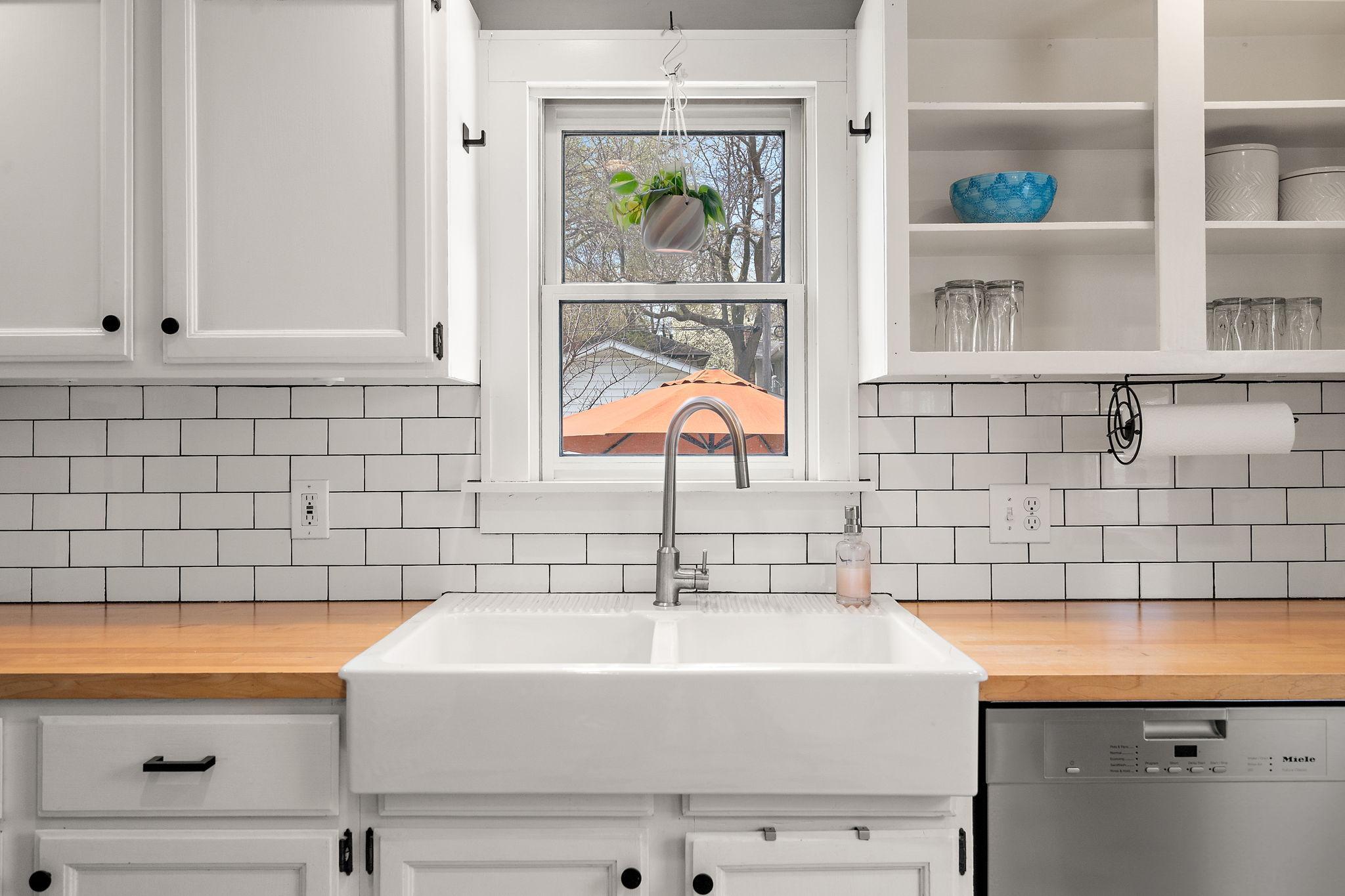 Butcher block countertops, subway tile backsplash and a classic farmhouse sink
