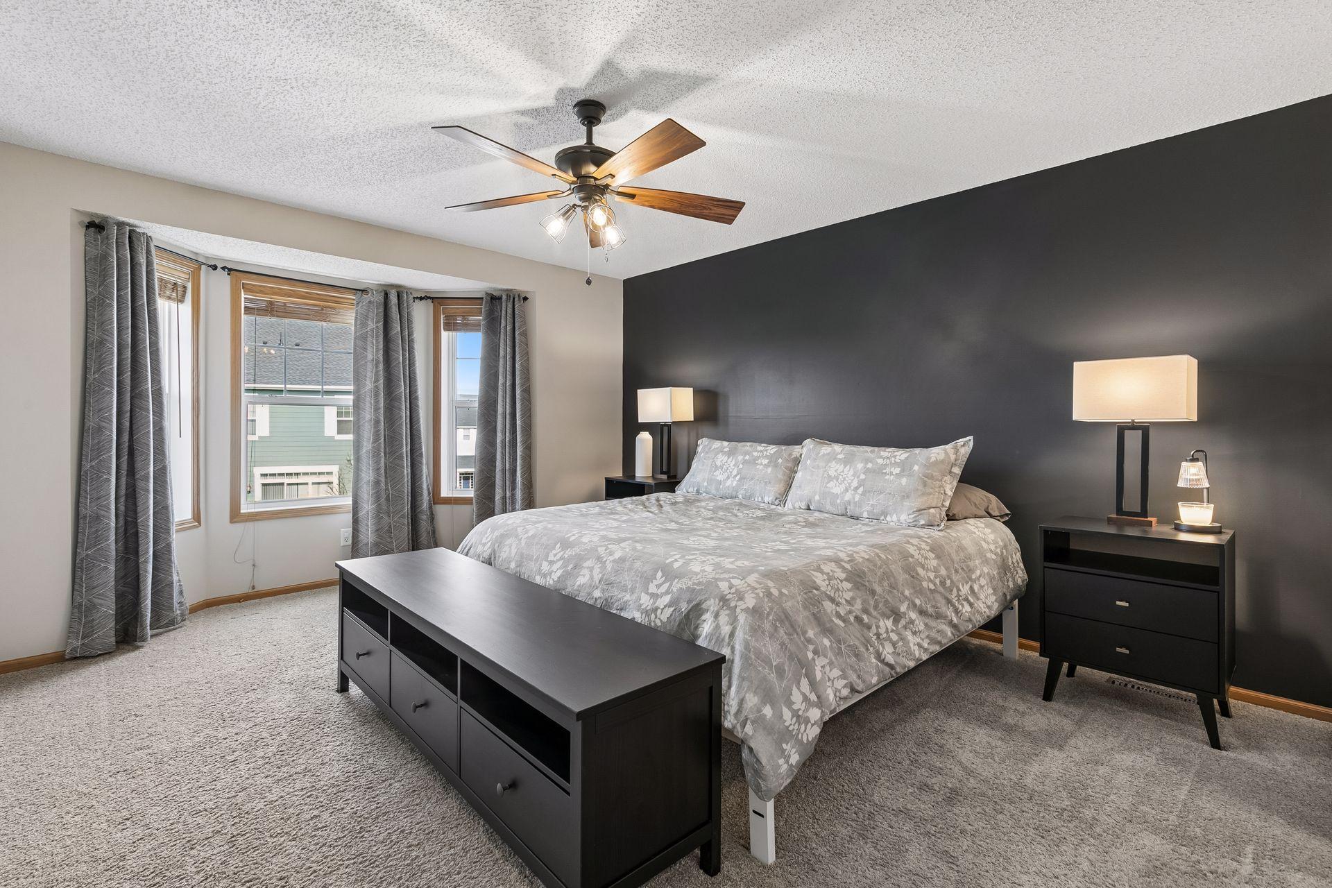 Spacious primary bedroom located on the upper level with large windows that flood natural light into the room.
