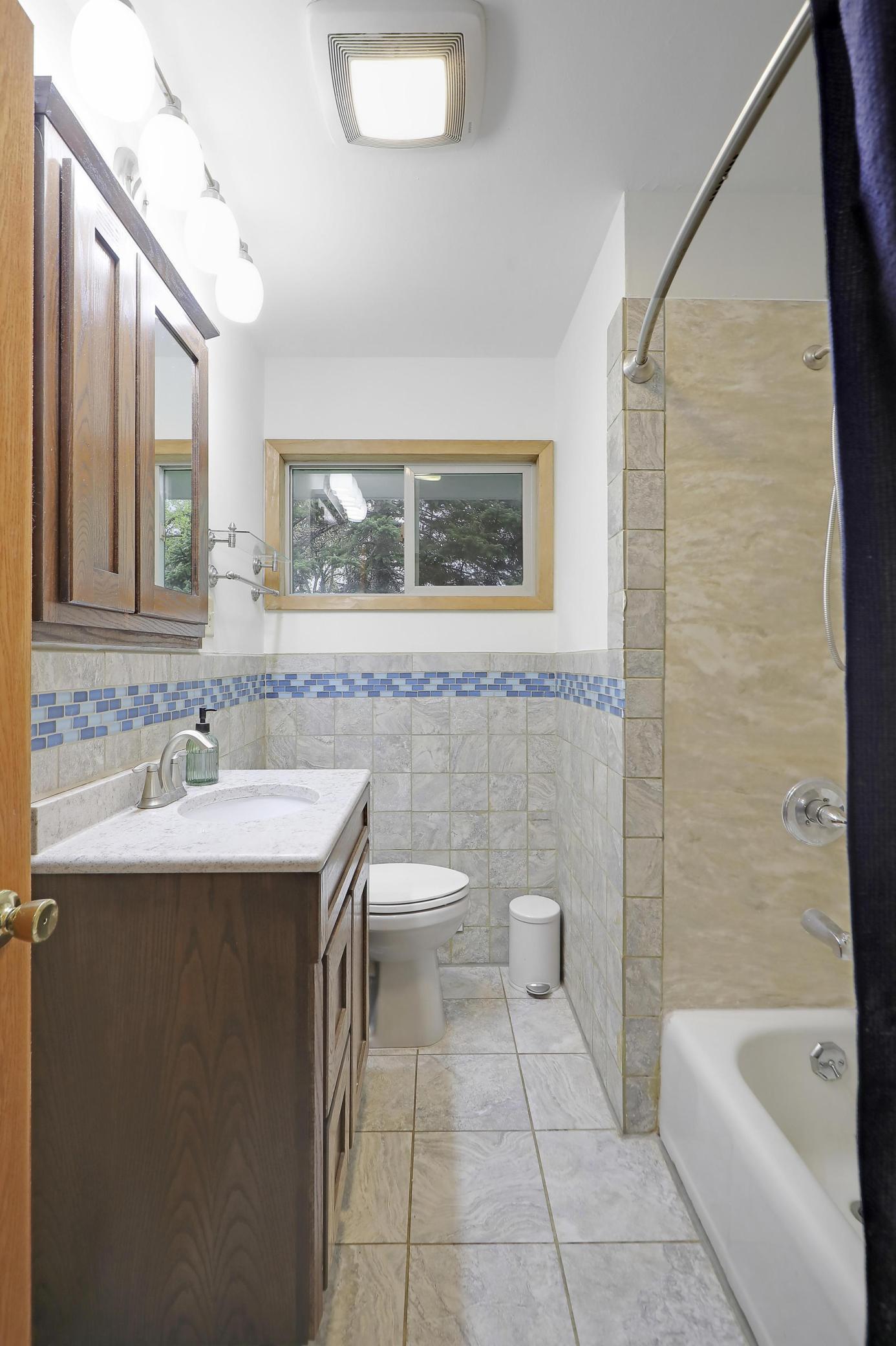 Main level full bathroom featuring ceramic floor tiling and walls.