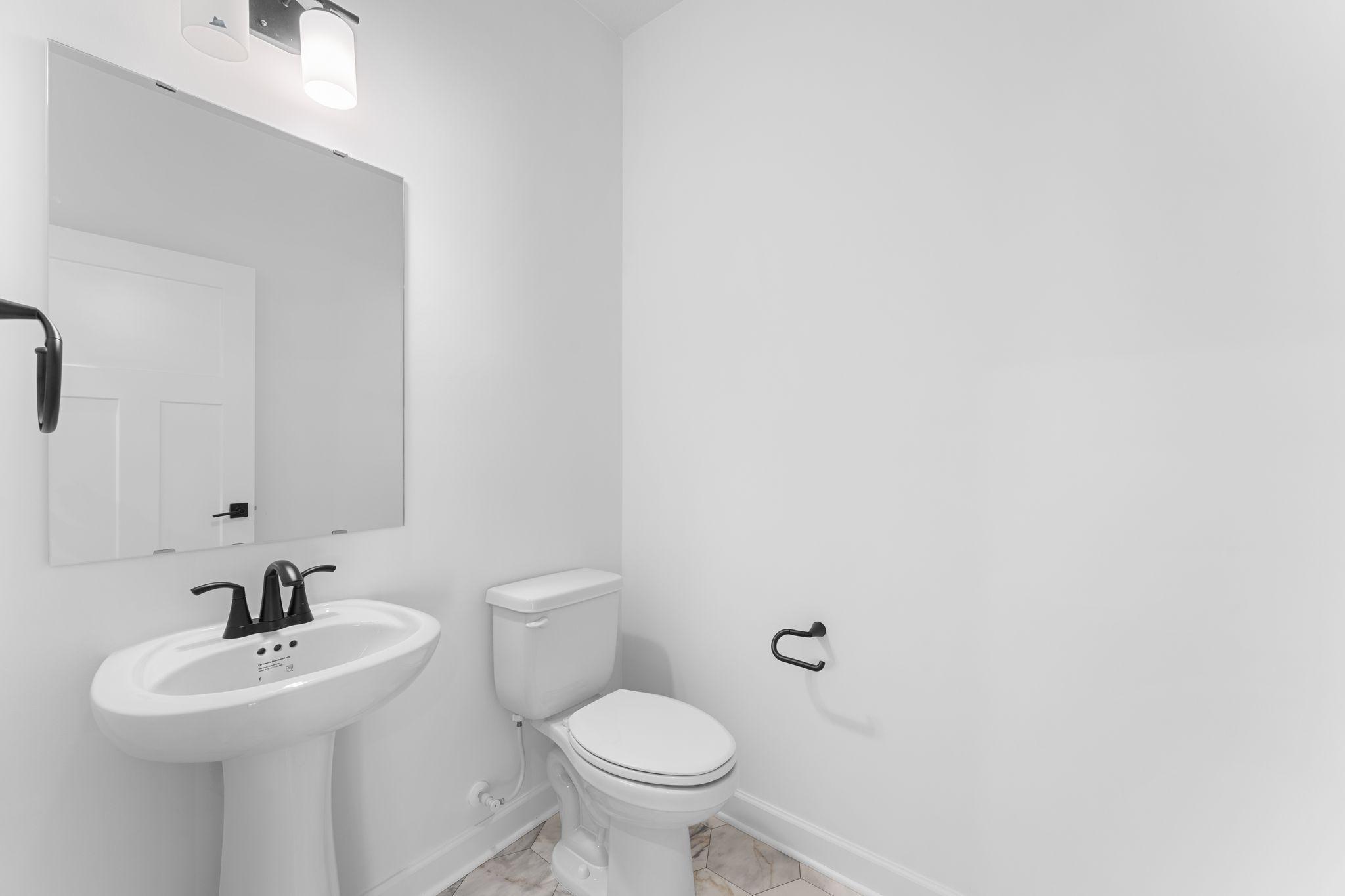 (Photo of a similar home, actual finishes may vary) A first-floor powder room is easily accessible from the communal living and dining spaces.