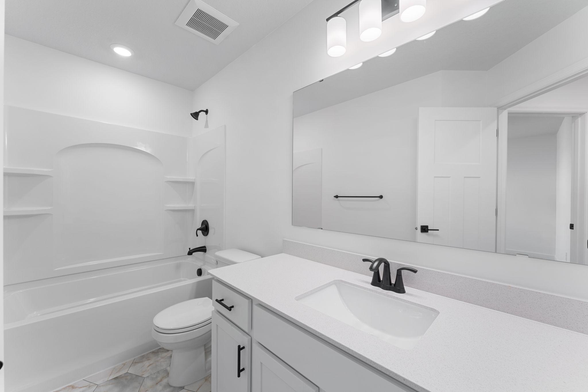 (Photo of a similar home, actual finishes may vary) This full second-floor bathroom features a wide single vanity and shower-tub combination.