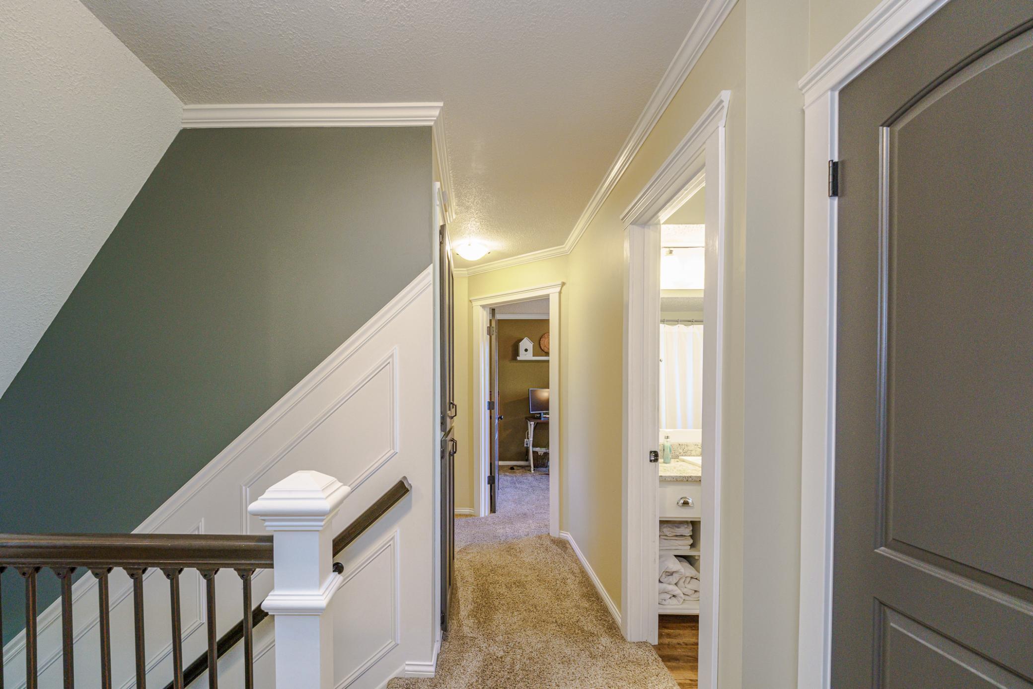 The upper level has four bedrooms and two baths. The staircase has paneled walls and iron balusters.
