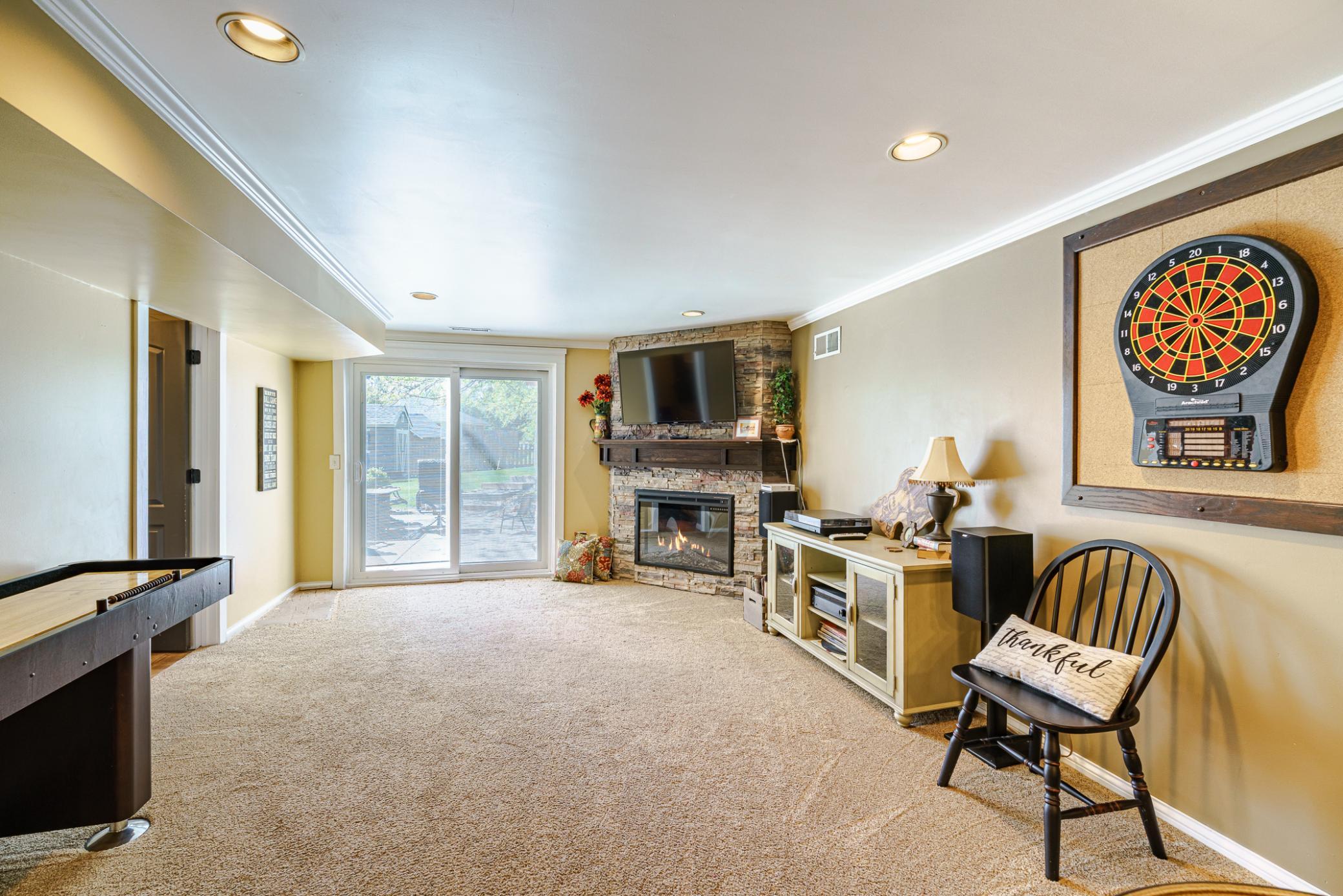 The lower level amusement area has a corner, gas fireplace with dry-stack stone to-the ceiling. The fireplace includes a wood mantle. This space also has crown molding and walks out to the backyard.