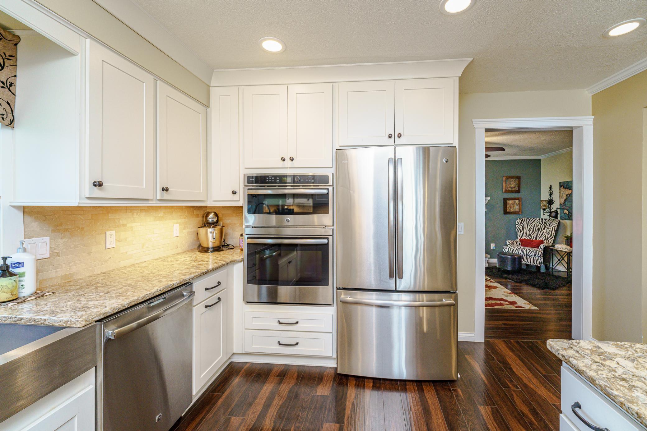 The appliances include a gas 5-burner cooktop with an overhead vent fan and double wall ovens.