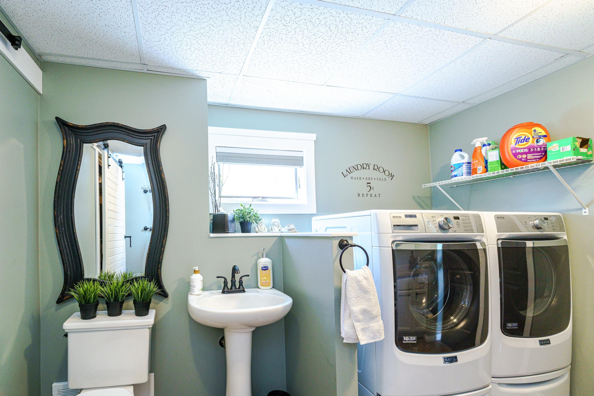 The laundry room is combined with the half bath and features front-loading Maytag appliances hidden behind sliding barn doors.