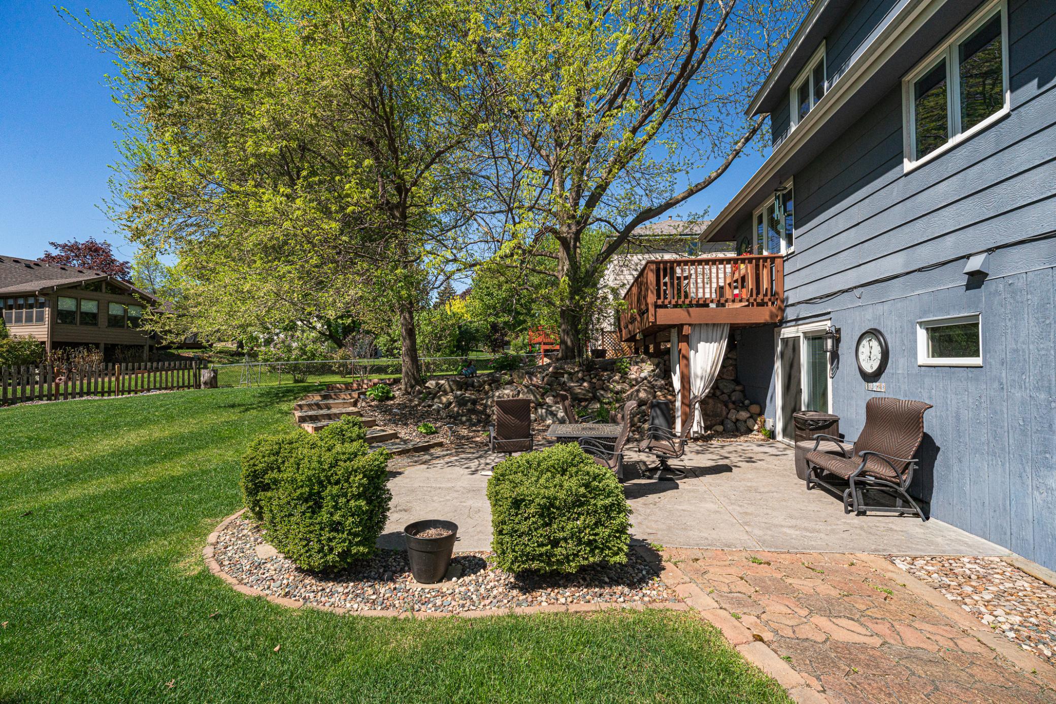 The lower level includes a stamped concrete patio surrounded by landscaping, with a paver footpath.