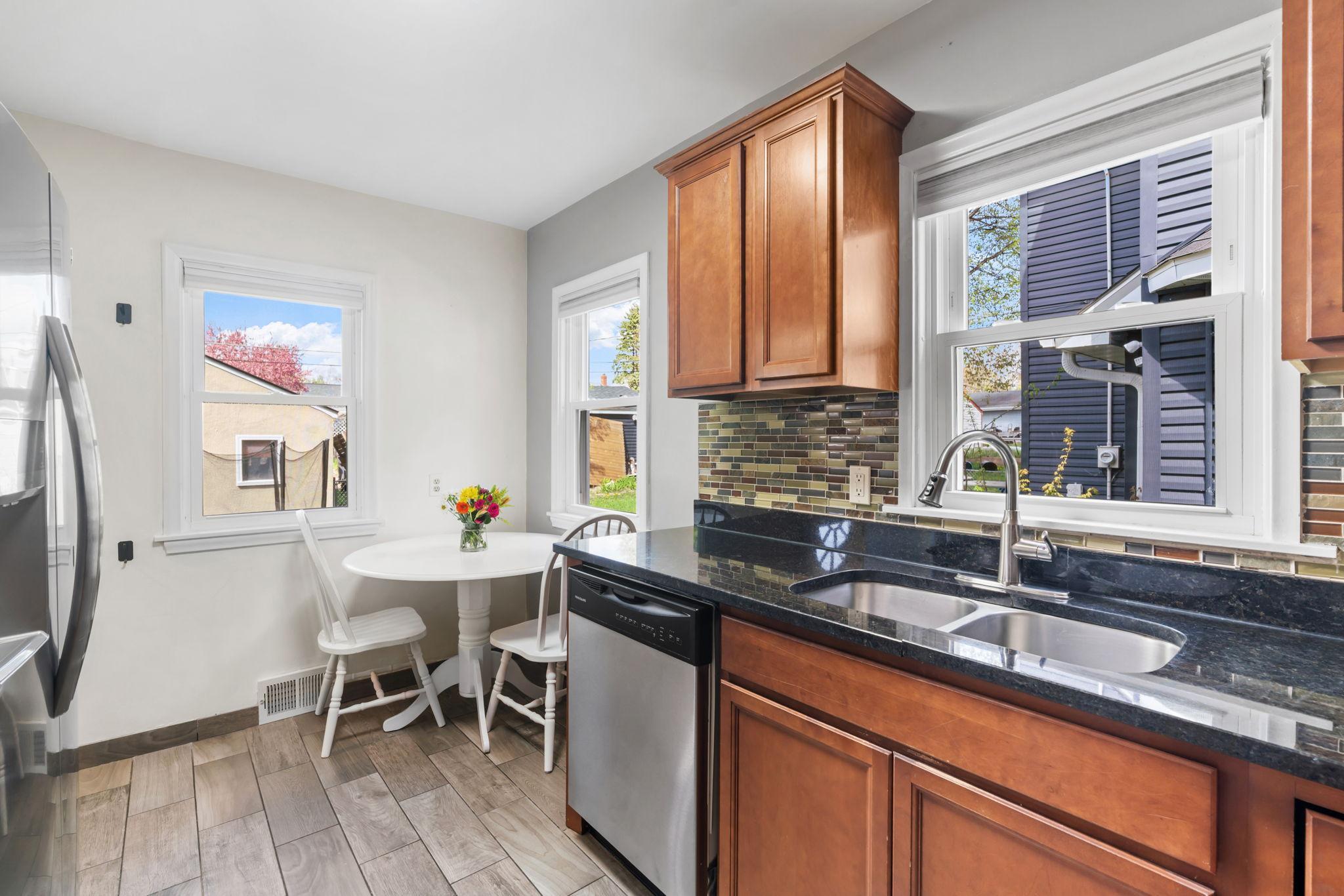 Rich, dark cabinets with granite countertops, tile backsplash, stainless steel appliances & and eat-in kitchen.