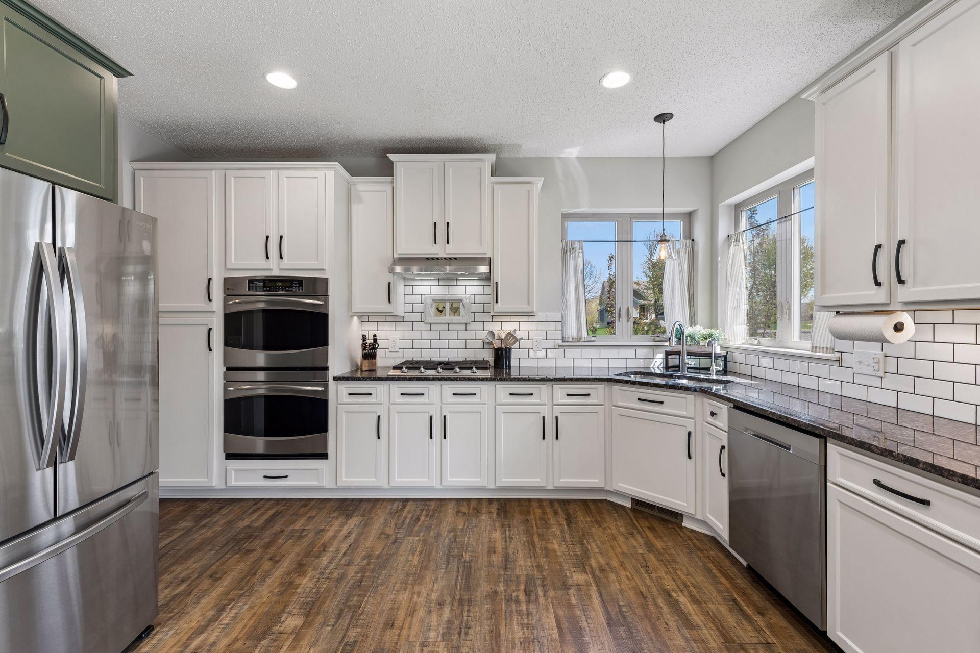 There is a subway tile backsplash with undercabinet lighting and granite counters.