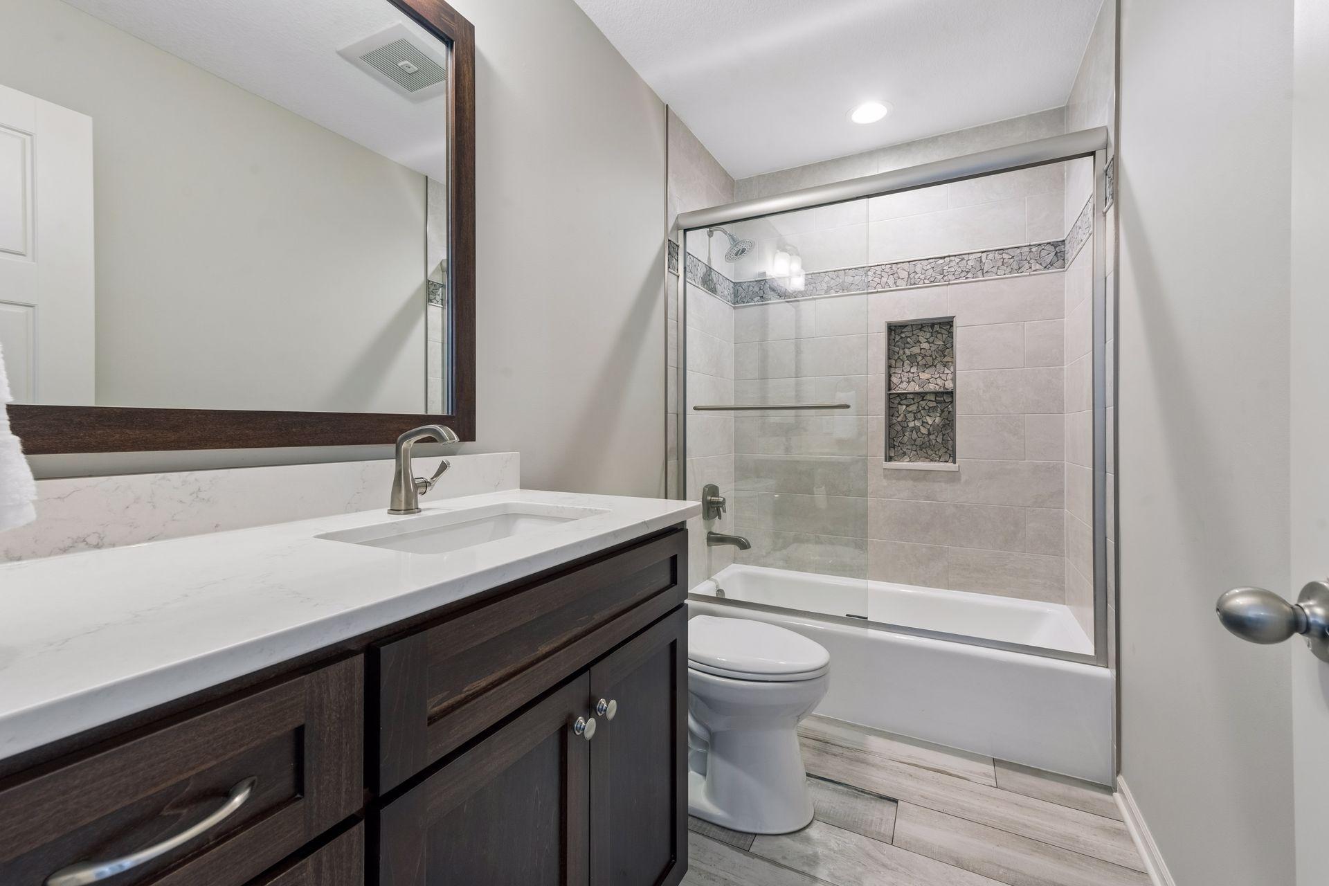 The full bath on the upper level has a vanity with a long counter and a custom tile surround on the tub/shower combination.