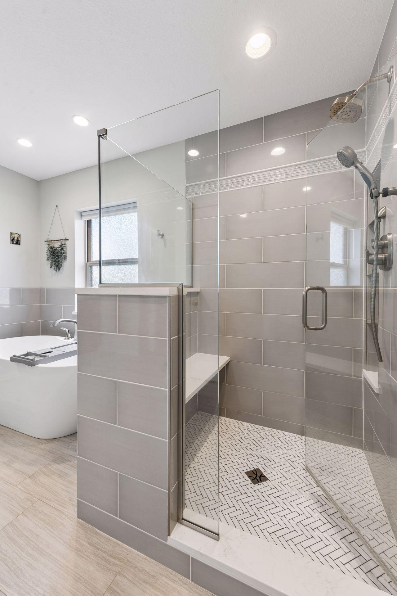 The tile shower has a seat and multiple shower heads.