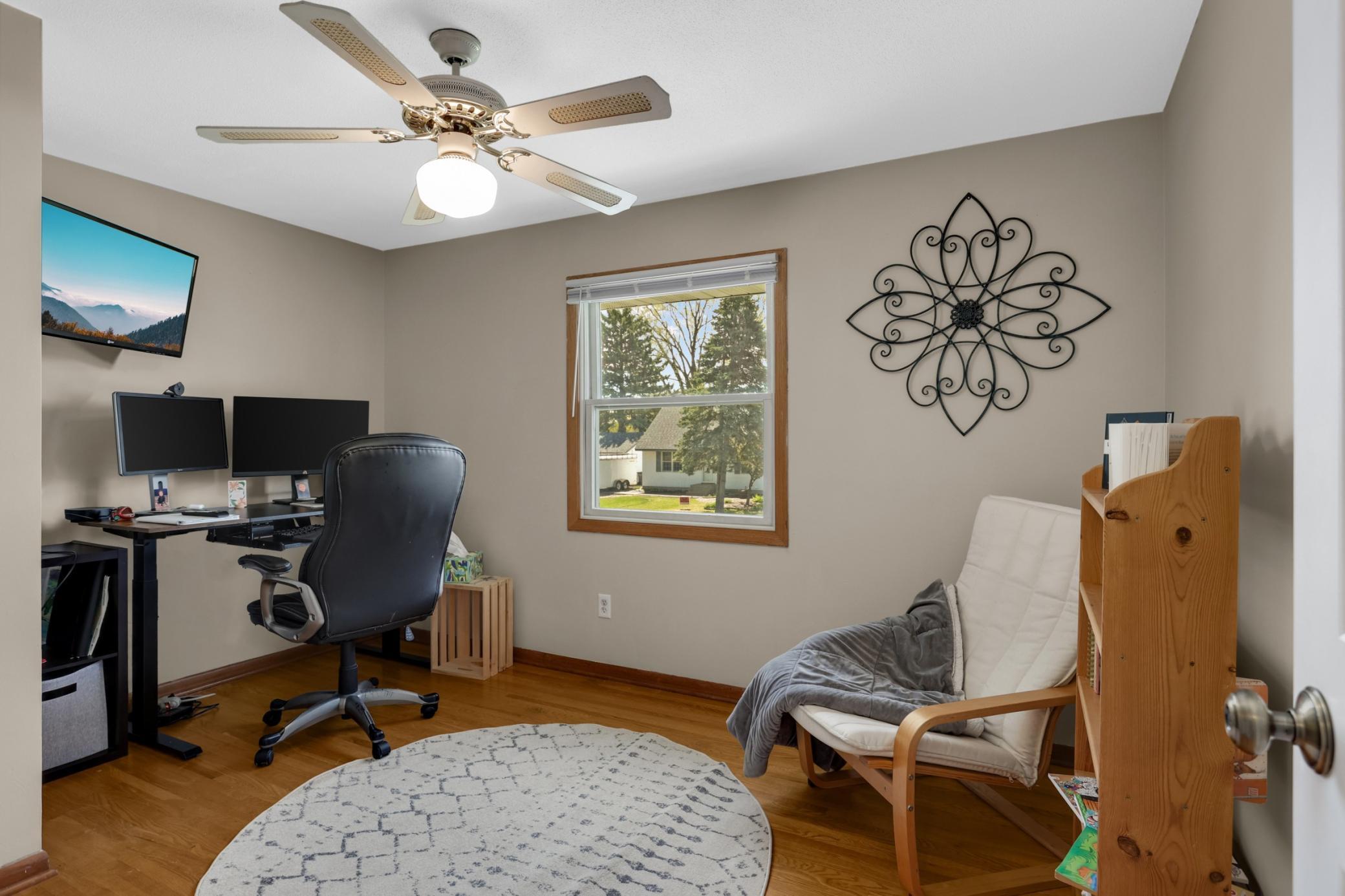 Another warm bedroom or office, with original wood flooring and a ceiling fan.