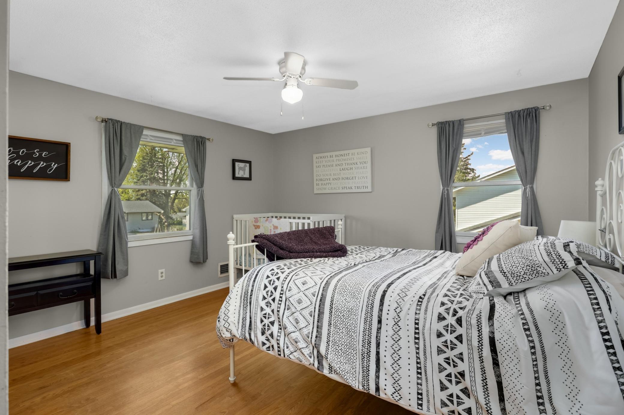 Third bedroom with double windows, another ceiling fan and the original hardwood flooring.