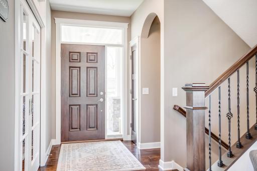 A sun-filled foyer welcomes you with rich hardwood floors and opens to a private office. The lovely arched opening shown leads to the powder bath.