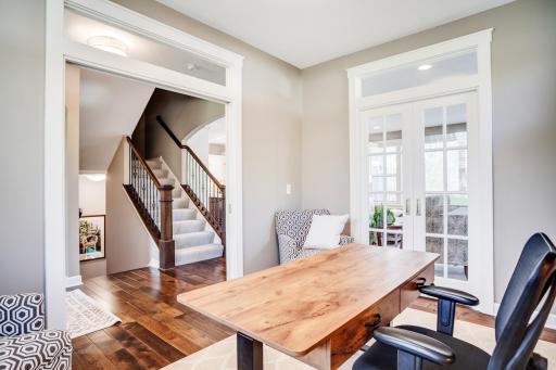 The office is framed by two sets of glass pocket doors, creating flexible separation from both the entry and great room.