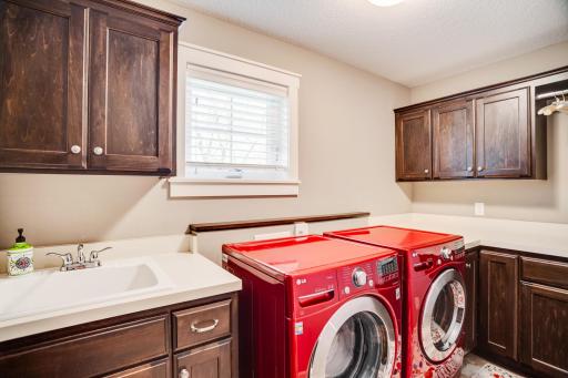 Fantastic upper-level laundry room is fully loaded with abundant cabinetry, utility sink, and generous workspace/folding counter.