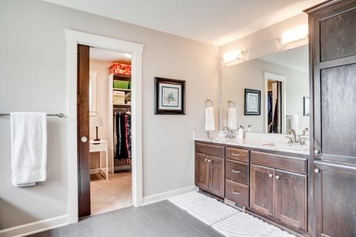 The spa-inspired en-suite bath offers a dual sink vanity with granite countertops, lots of storage, tile floors, and private water closet.