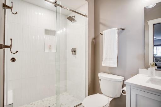 The 3/4 bath features a beautifully tiled walk-in shower and is ready to accommodate guests while entertaining + is conveniently located near the lower-level bedroom.