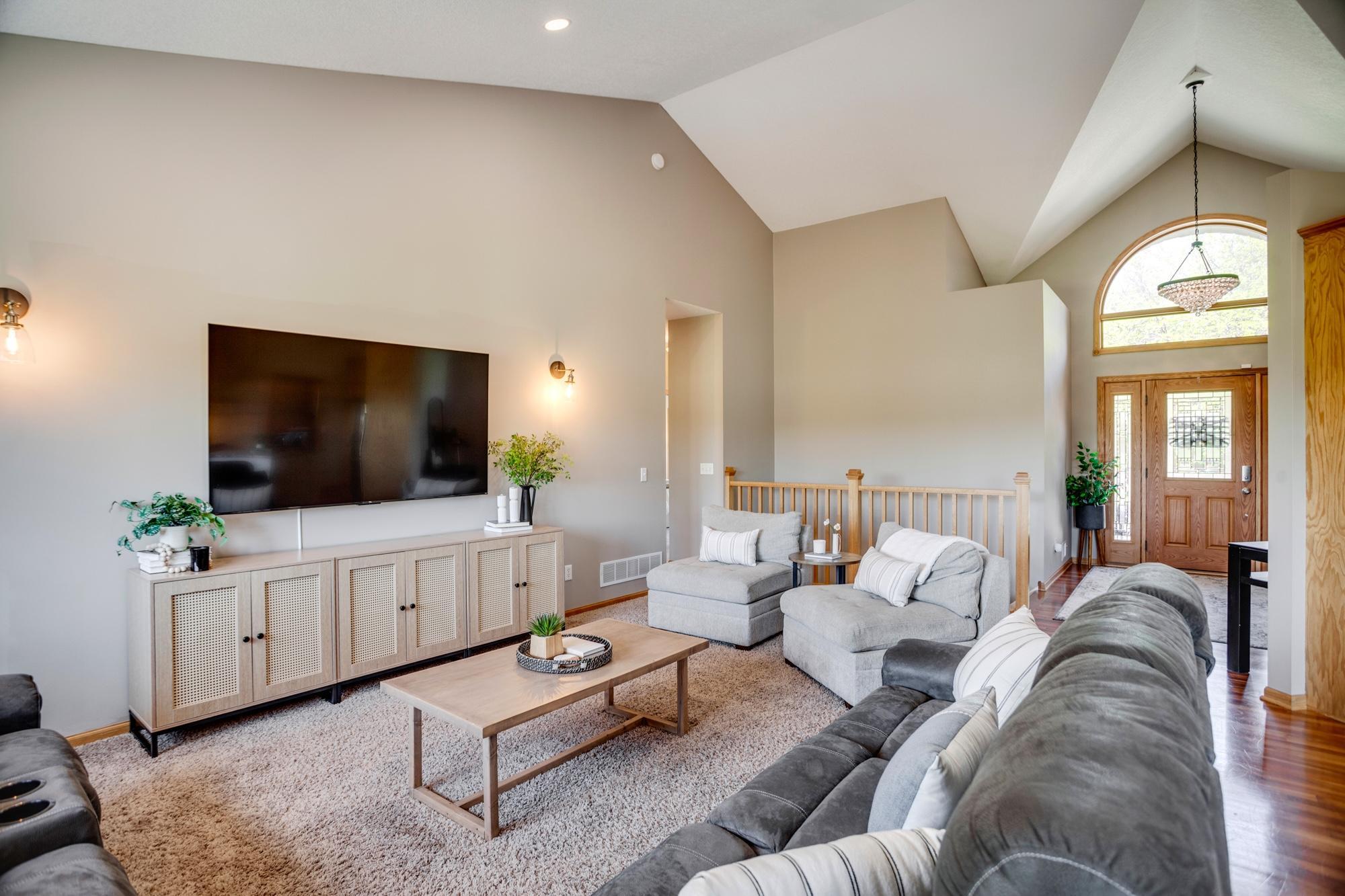 Bright and open main-level level living room with vaulted ceilings and a wall of windows