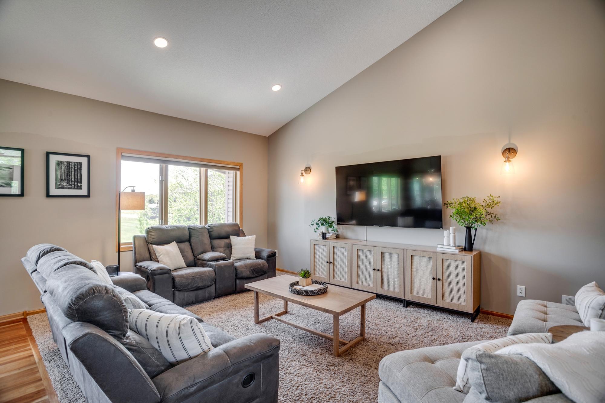 Bright and open main-level level living room with vaulted ceilings and a wall of windows