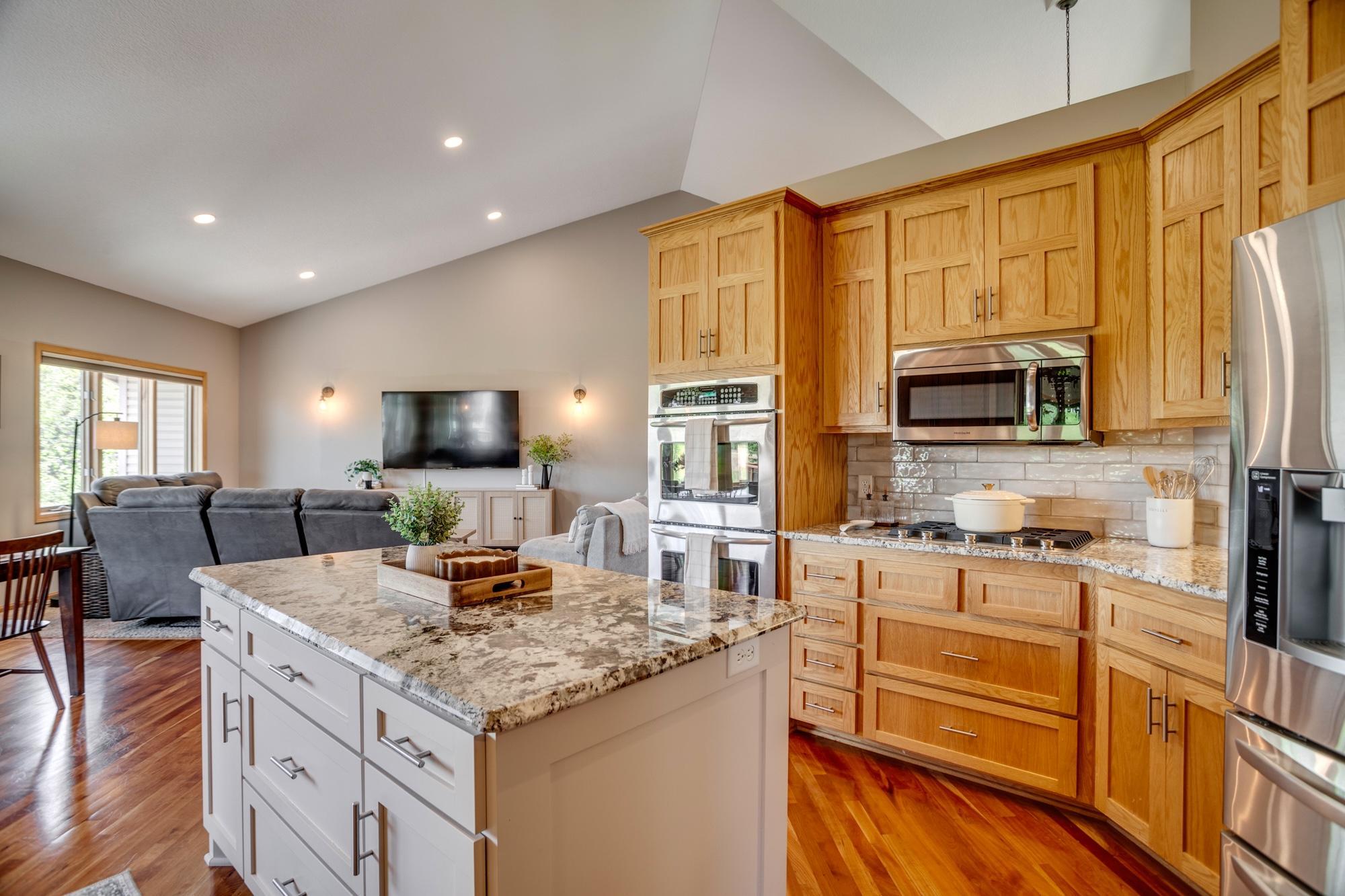 Gourmet kitchen equipped with granite countertops, stainless-steel appliances, a double oven and center island