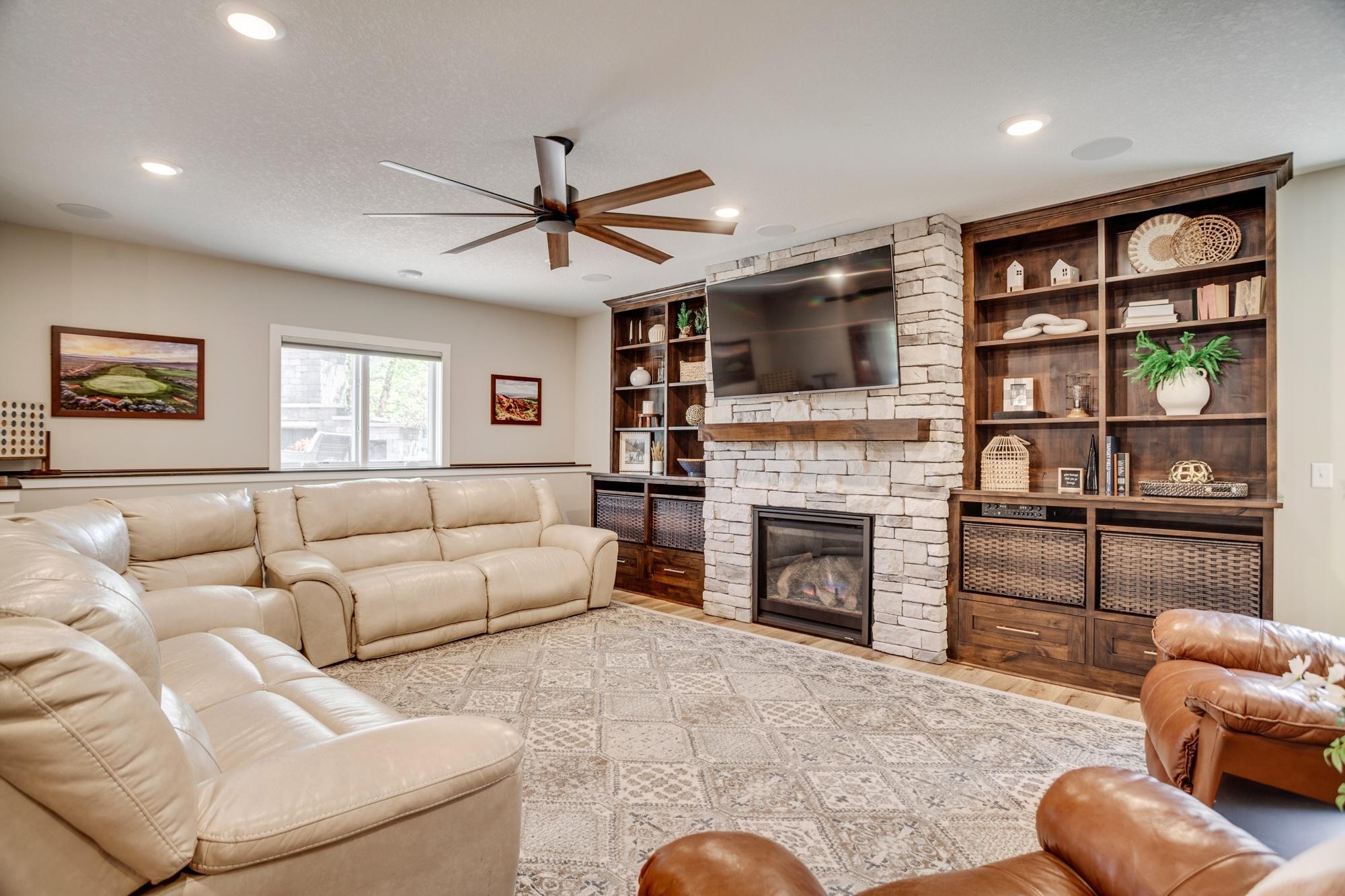 Spacious lower-level family room centered around a beautiful stone fireplace and built-ins