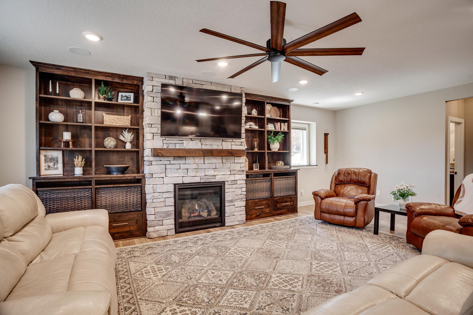 Spacious lower-level family room centered around a beautiful stone fireplace and built-ins