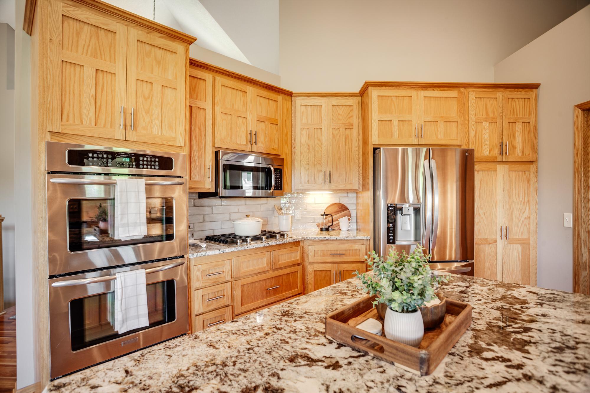 Gourmet kitchen equipped with granite countertops, stainless-steel appliances, a double oven and center island