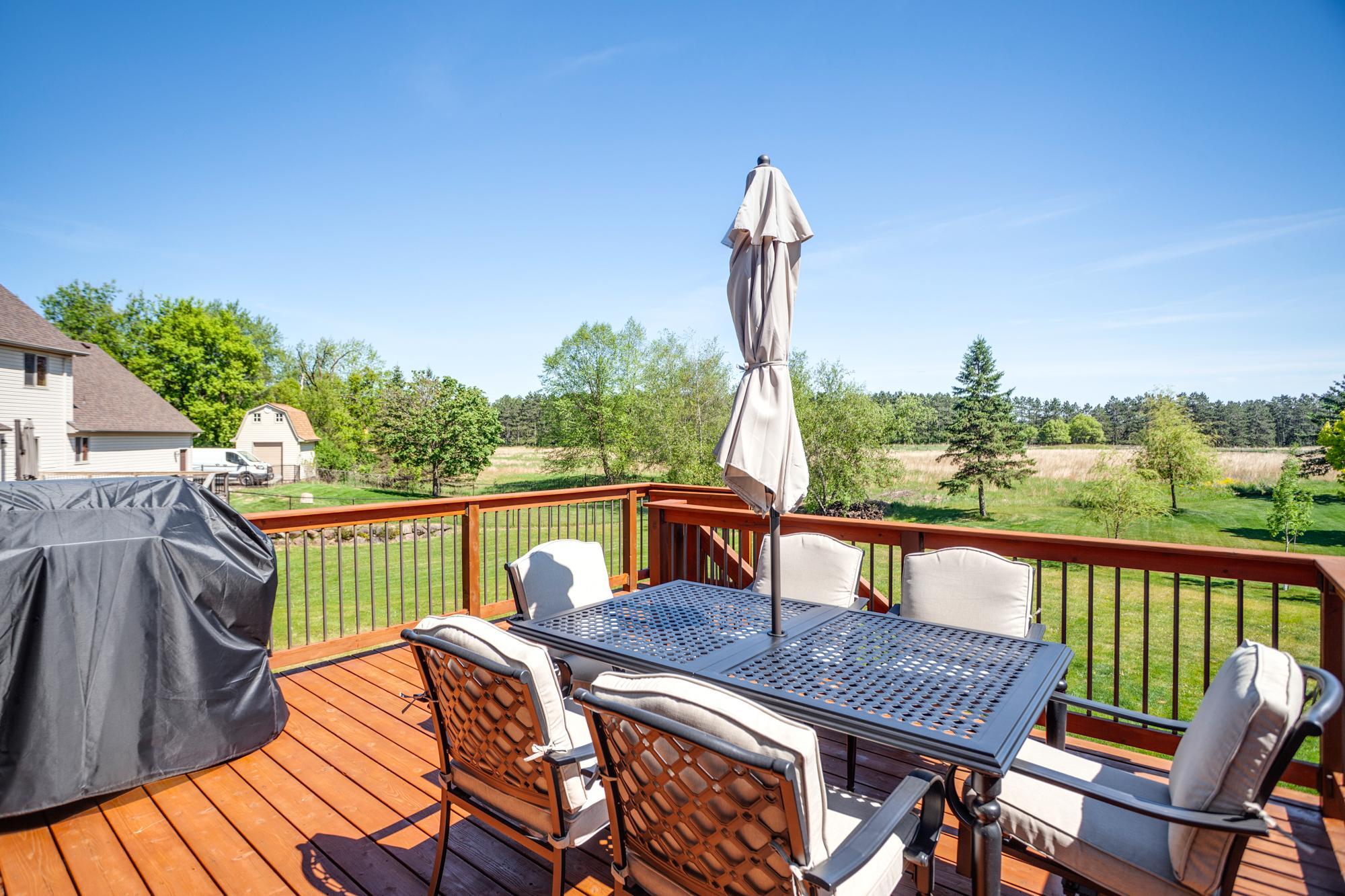 The deck and patio feature expansive views of the open fields behind the home