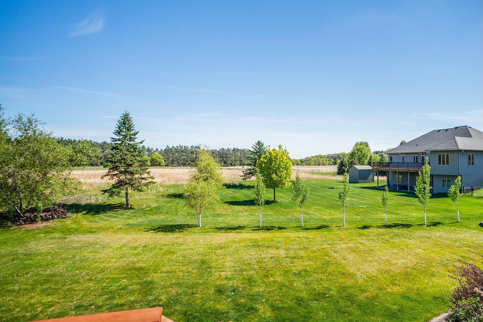 The deck and patio feature expansive views of the open fields behind the home