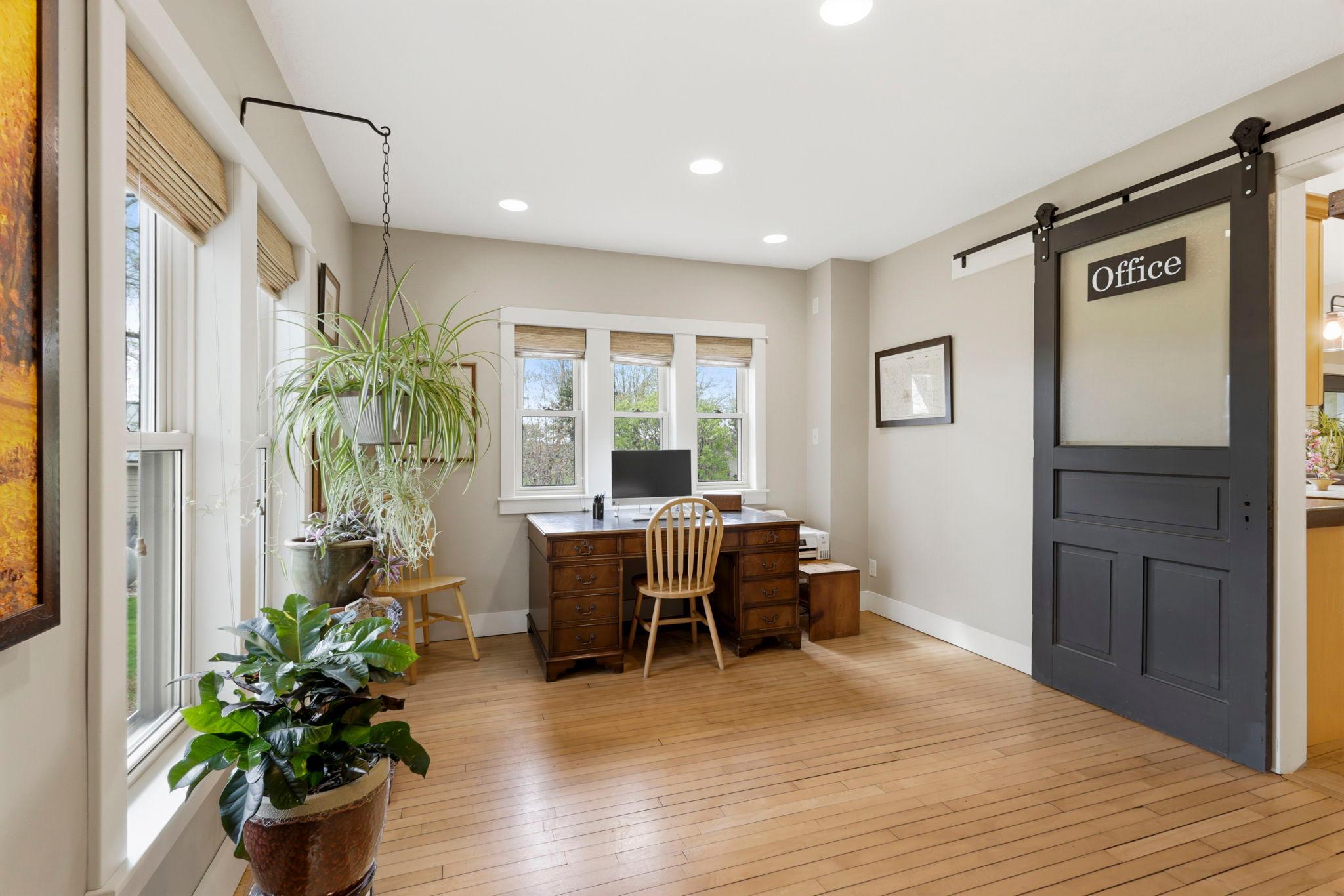 Dedicated office space featuring sliding barn-style doors and large windows overlooking the property.