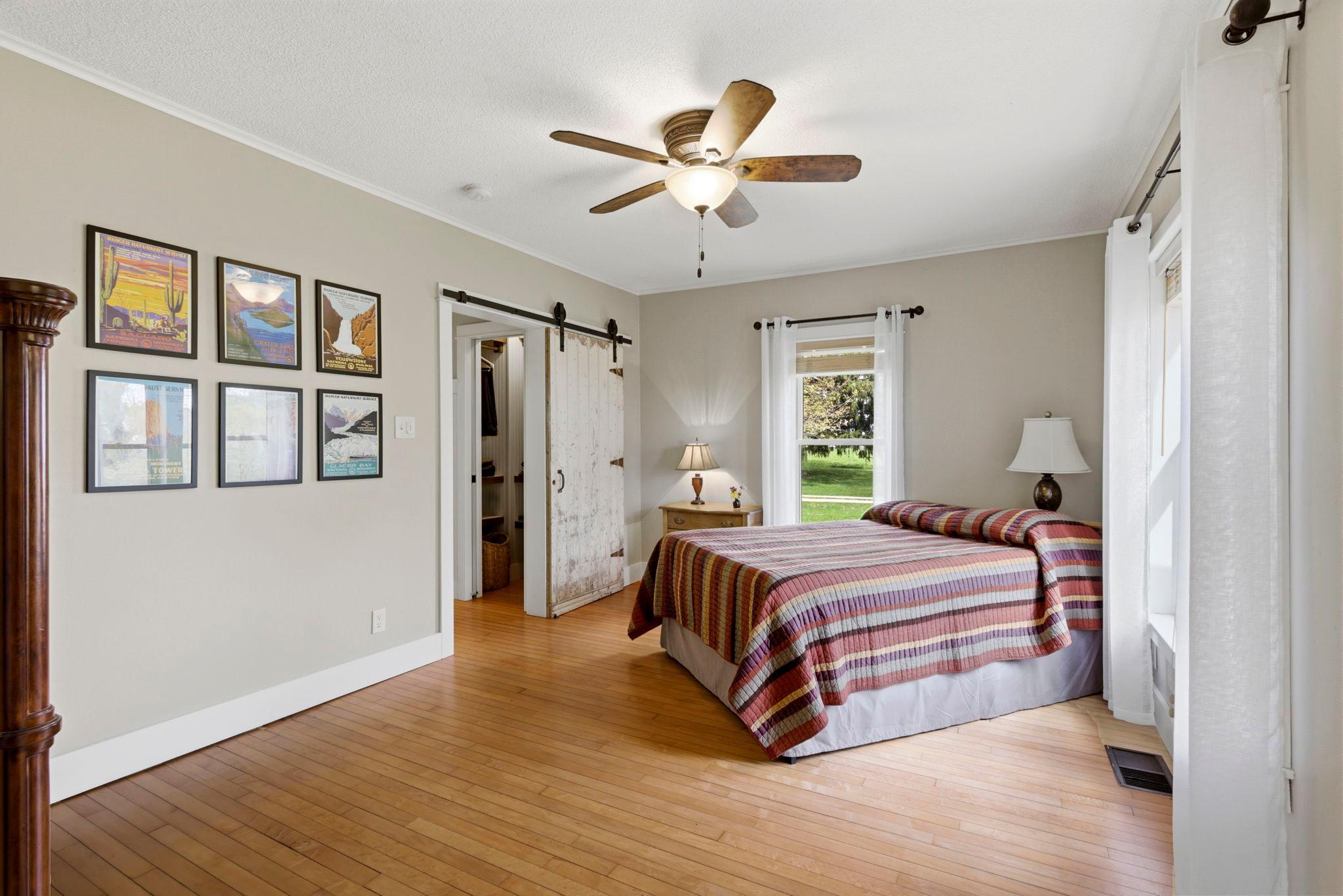 Generous primary bedroom with hardwood floors, natural light, and serene countryside views.