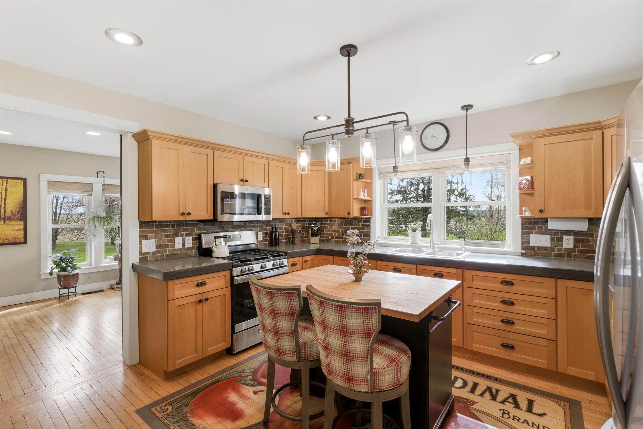Updated kitchen with warm wood cabinetry, butcher block island, and stylish lighting fixtures.