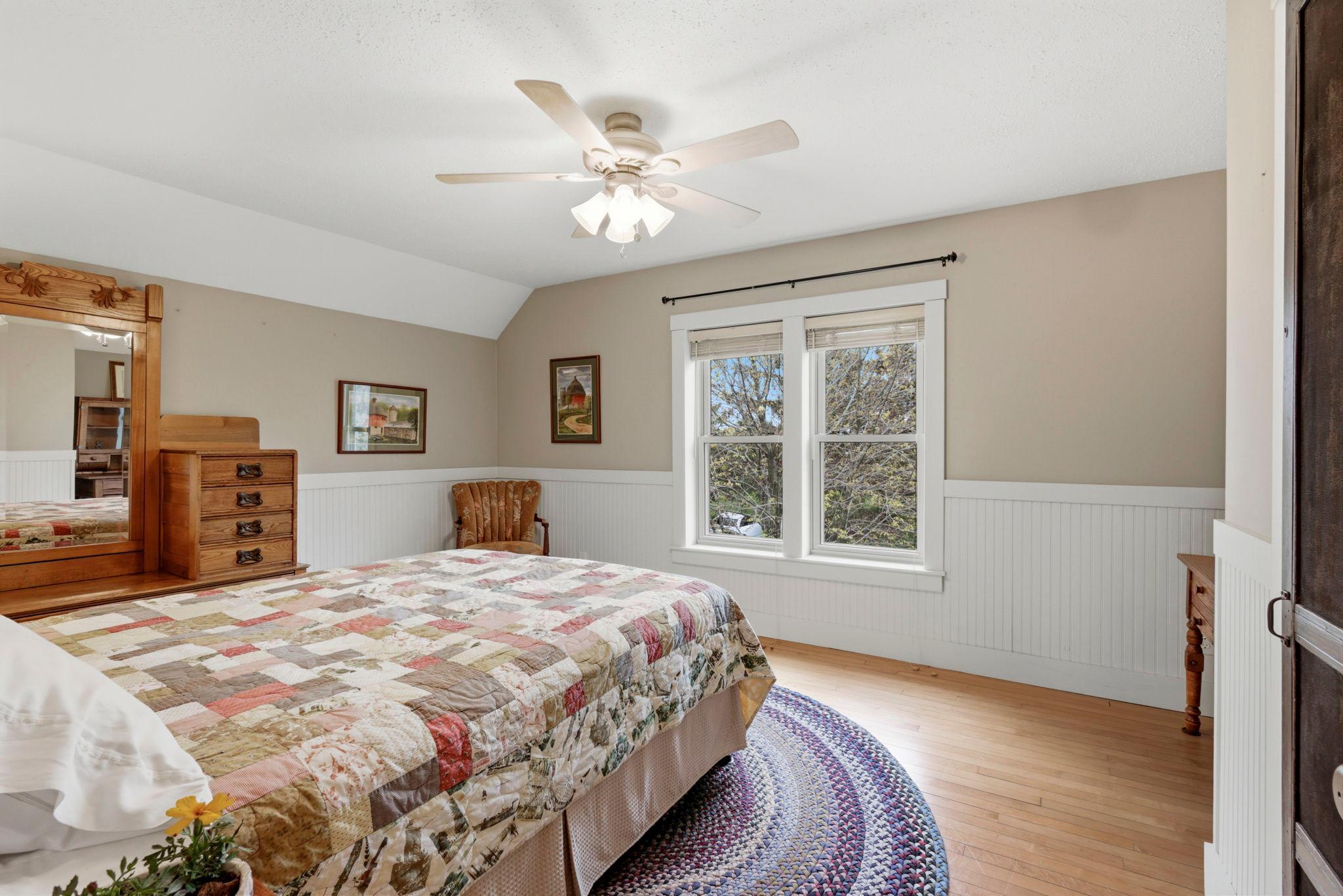 Spacious bedroom with original hardwood floors, neutral tones, and classic farmhouse charm.
