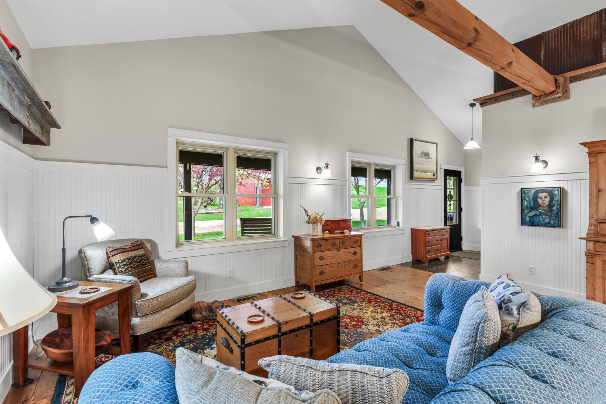 Bright and inviting main living area with warm wood tones, oversized windows, and charming farmhouse character.