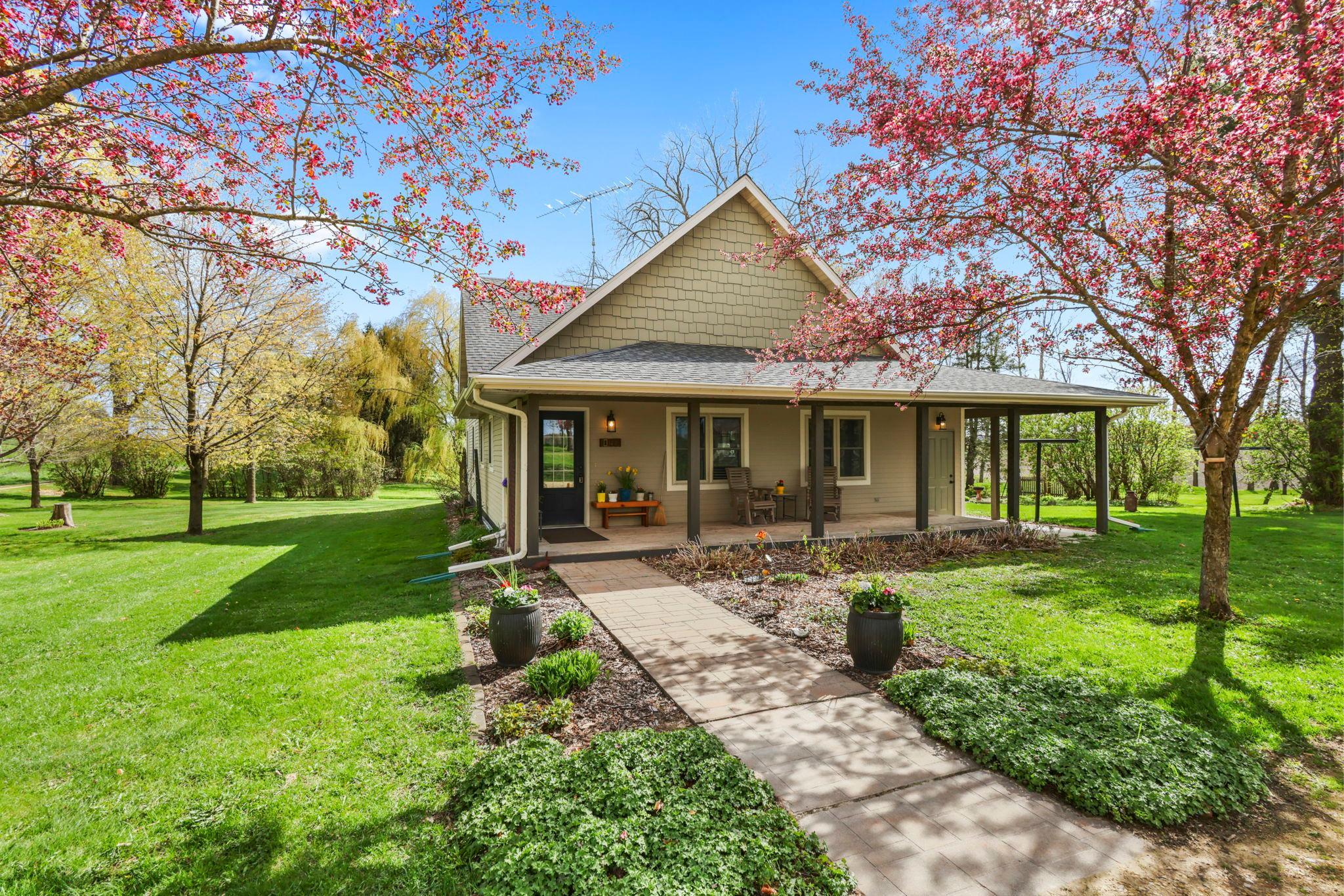 Welcome Home! Covered front porch framed by blooming trees and beautiful landscape.