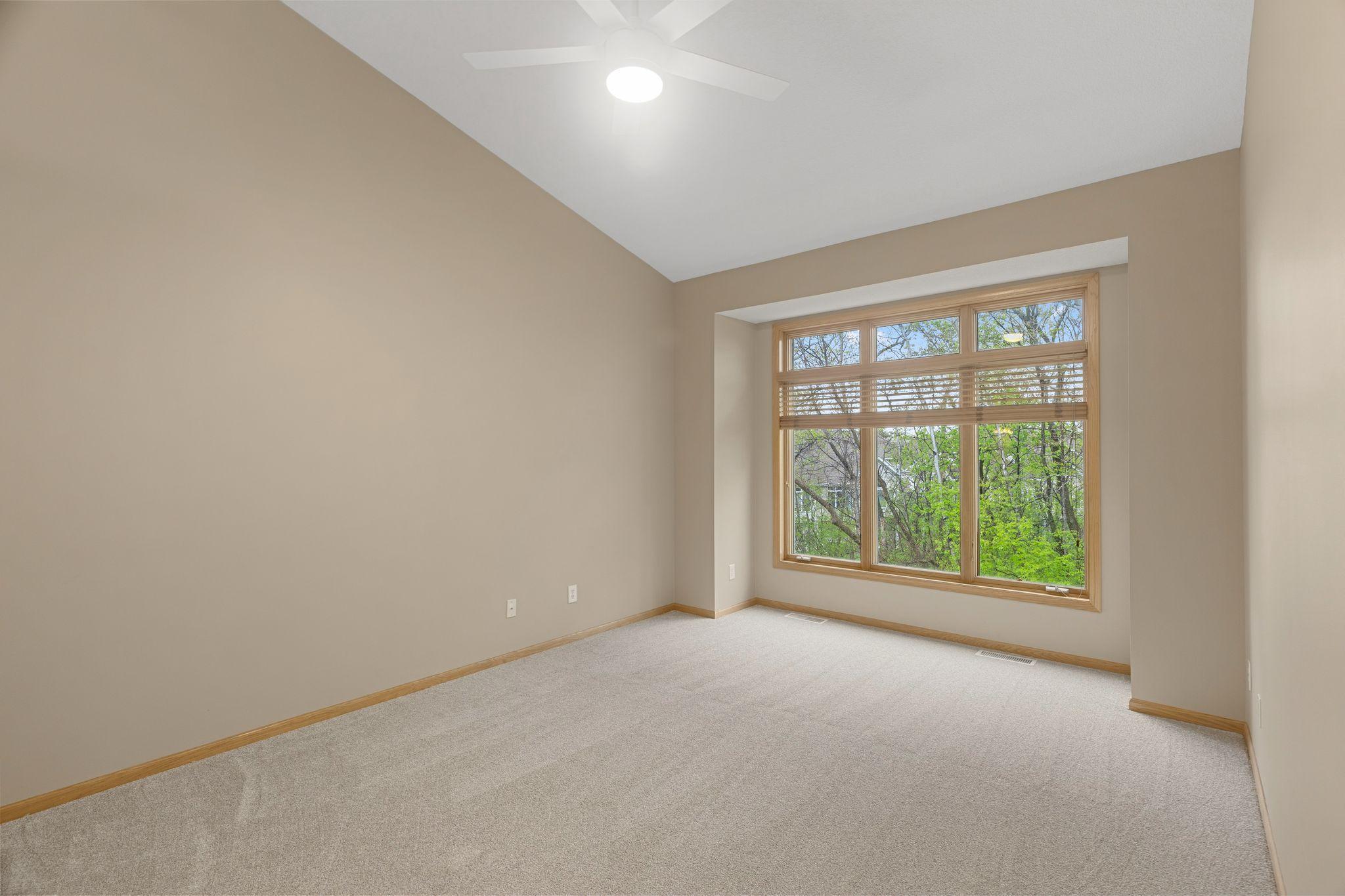 Spacious primary bedroom with vaulted ceilings, large windows, and peaceful backyard views.