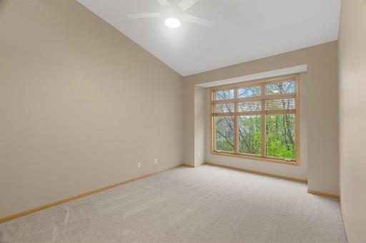 Spacious primary bedroom with vaulted ceilings, large windows, and peaceful backyard views.
