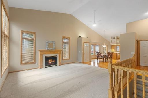 Bright and open vaulted living room featuring soaring ceilings, fresh carpet, and a cozy fireplace.