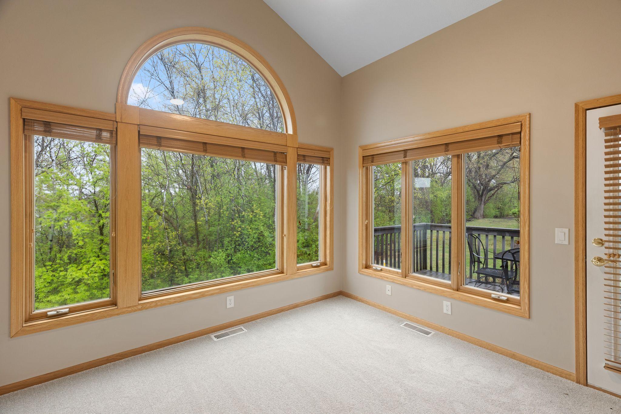 Stunning sunroom with oversized windows, peaceful wooded views, and direct access to the private deck.
