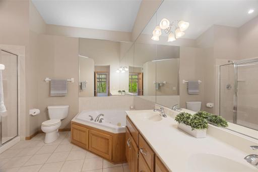 Large primary bathroom featuring double vanity, soaking tub, separate shower, and plenty of natural light.