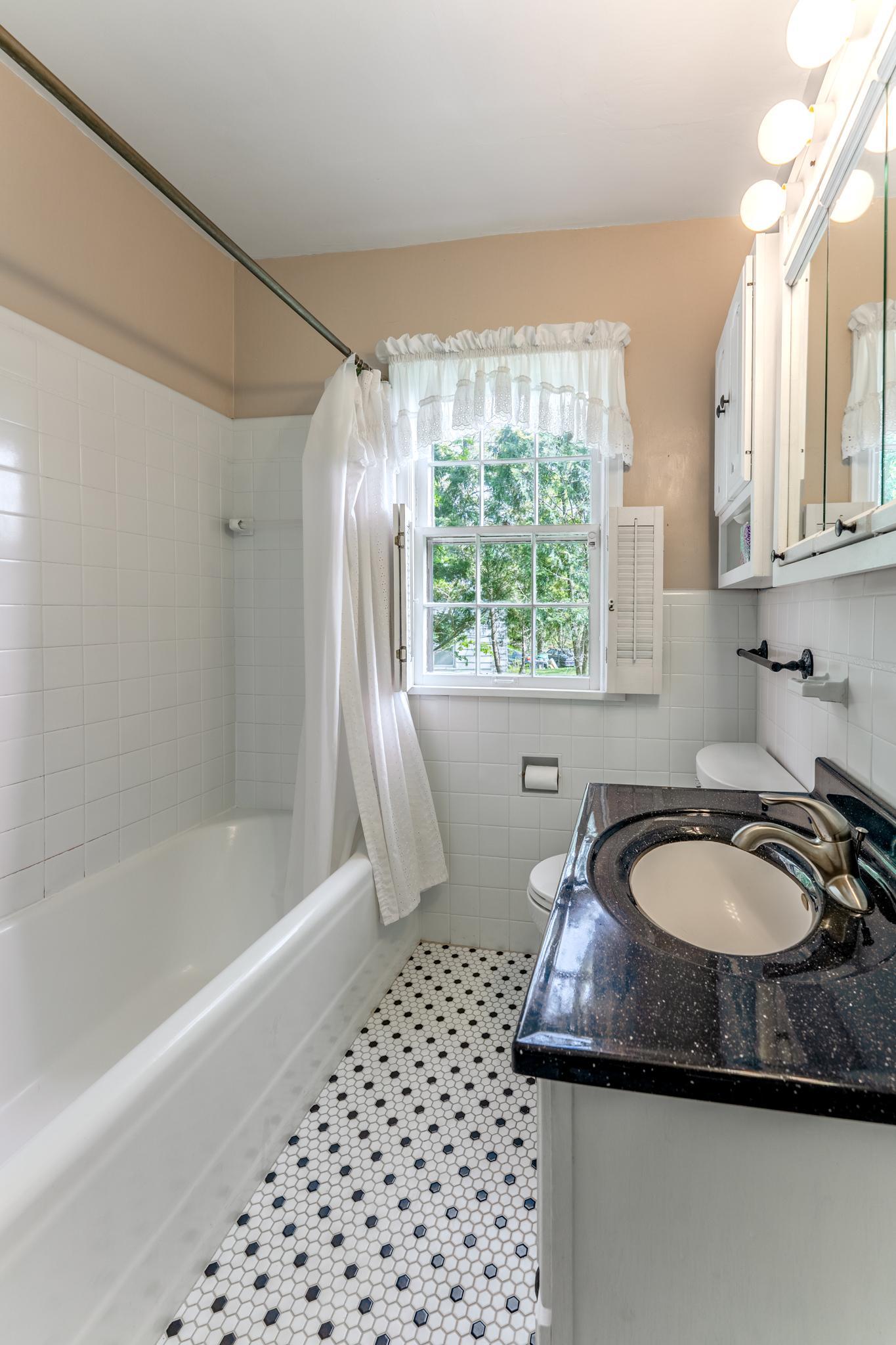 Main floor bathroom with tiled tub area and classic tile floor.