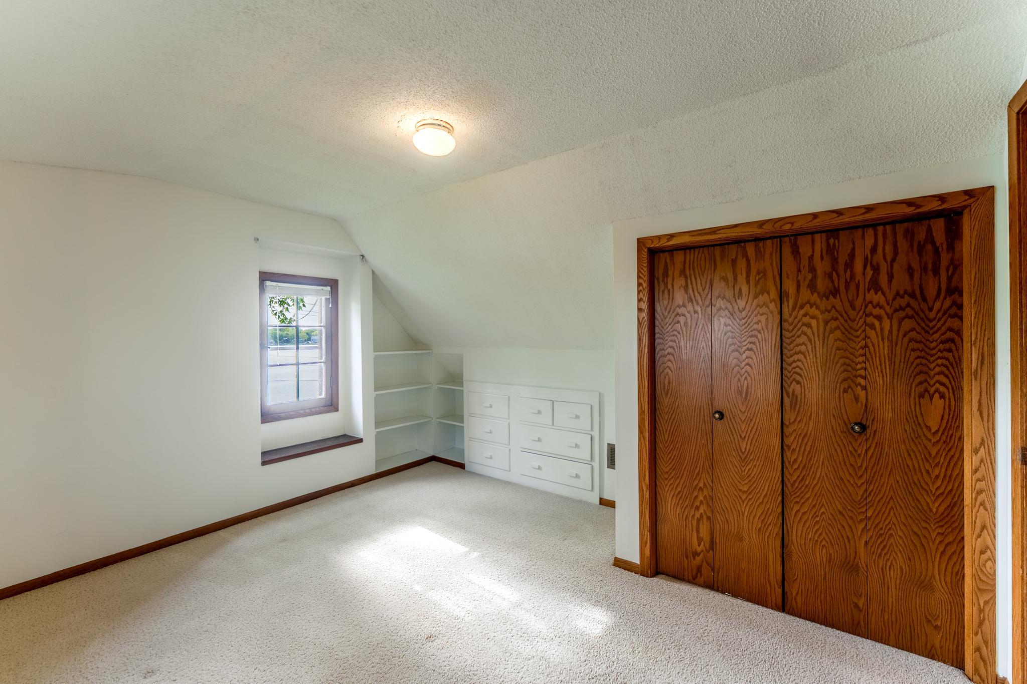 Upper level bedroom with a window seat and built-ins tucked under the eaves. So much charm in this room. (Bedroom3)