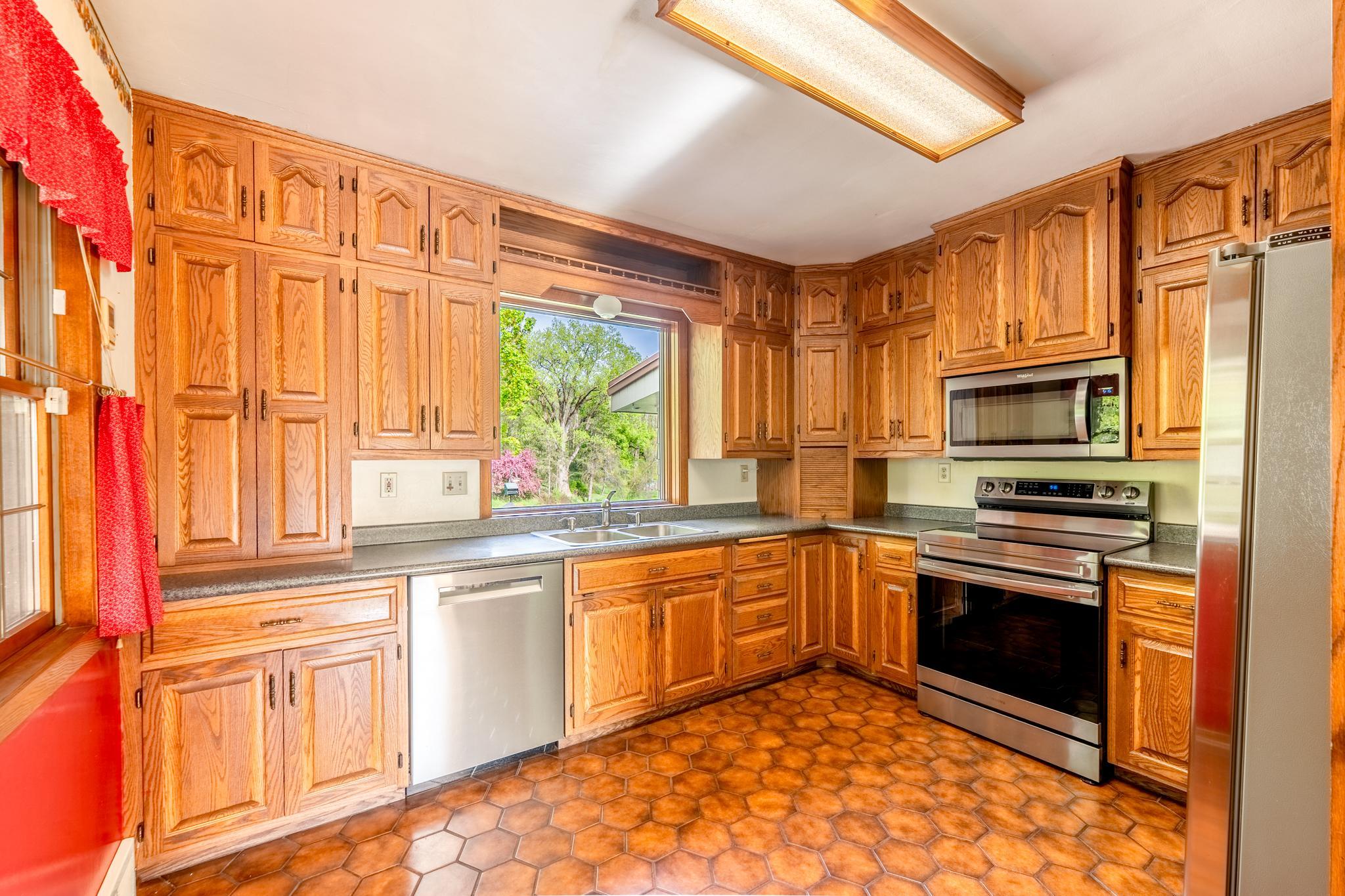 Plenty of kitchen cabinetry and a window with sweeping views of the backyard. Note the updated stainless steel appliances.
