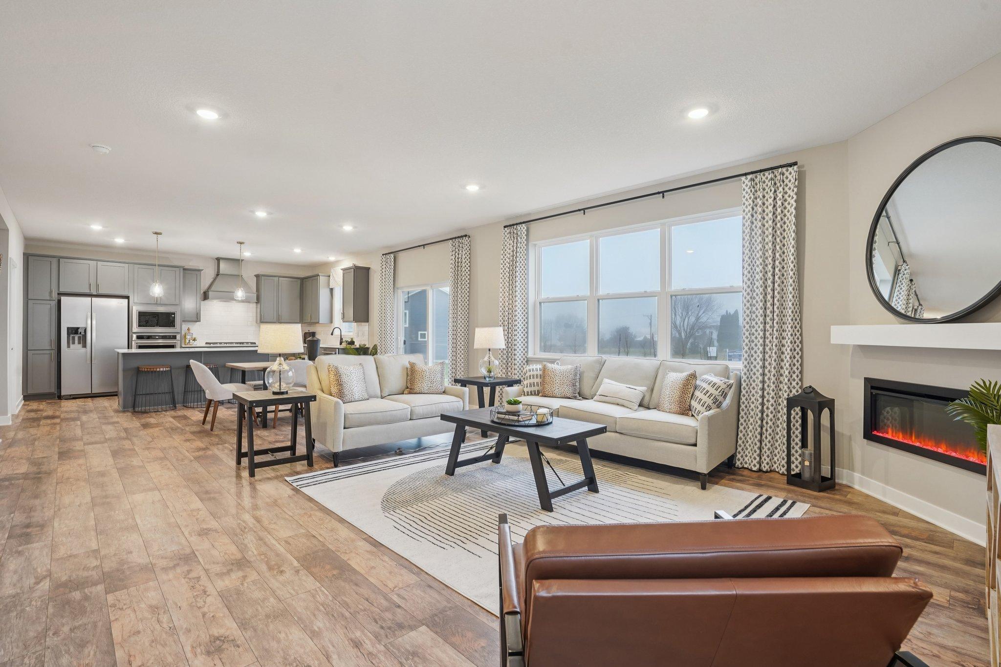 The main level includes large windows and a sliding door to fill the space with natural light. Photo of model home, fireplace surround and finishes will vary.