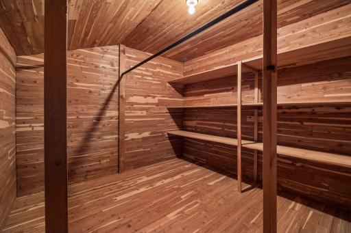 walk-in cedar closet with shelving and hanging storage off of primary bedroom